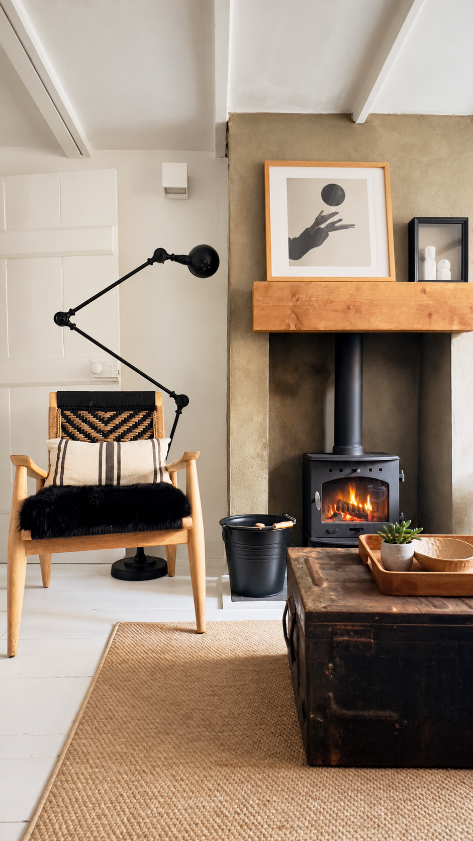 Dunroamin living room with a woven armchair, glowing log burner and a succulent on the vintage trunk