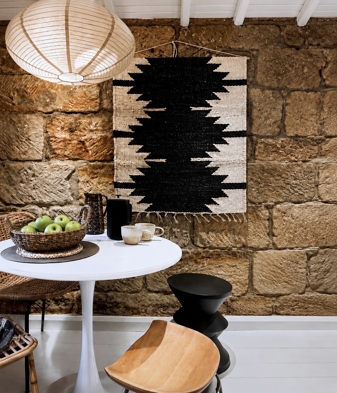 Dining table with green apples beneath a paper lantern beside the original stone wall